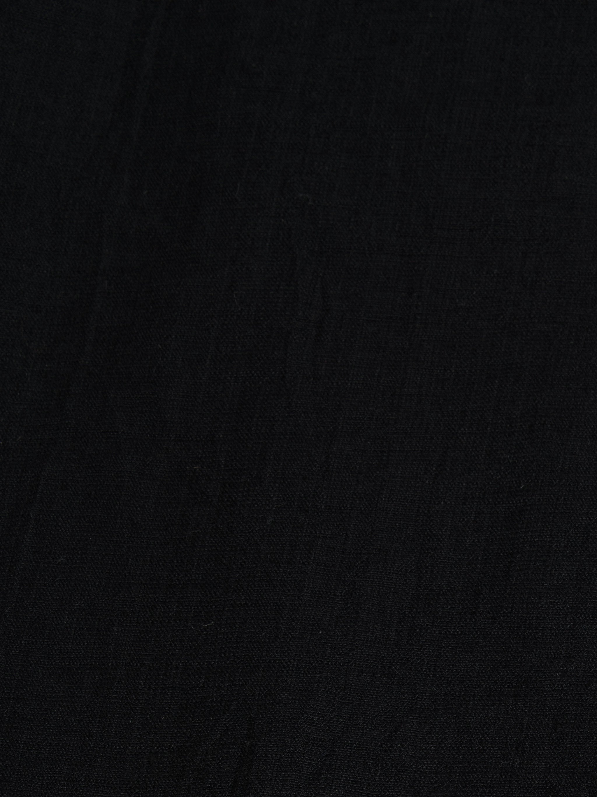 Close-up of Black palazzo pants showing the texture of the textured cotton fabricfor the modest, wide-leg cut.